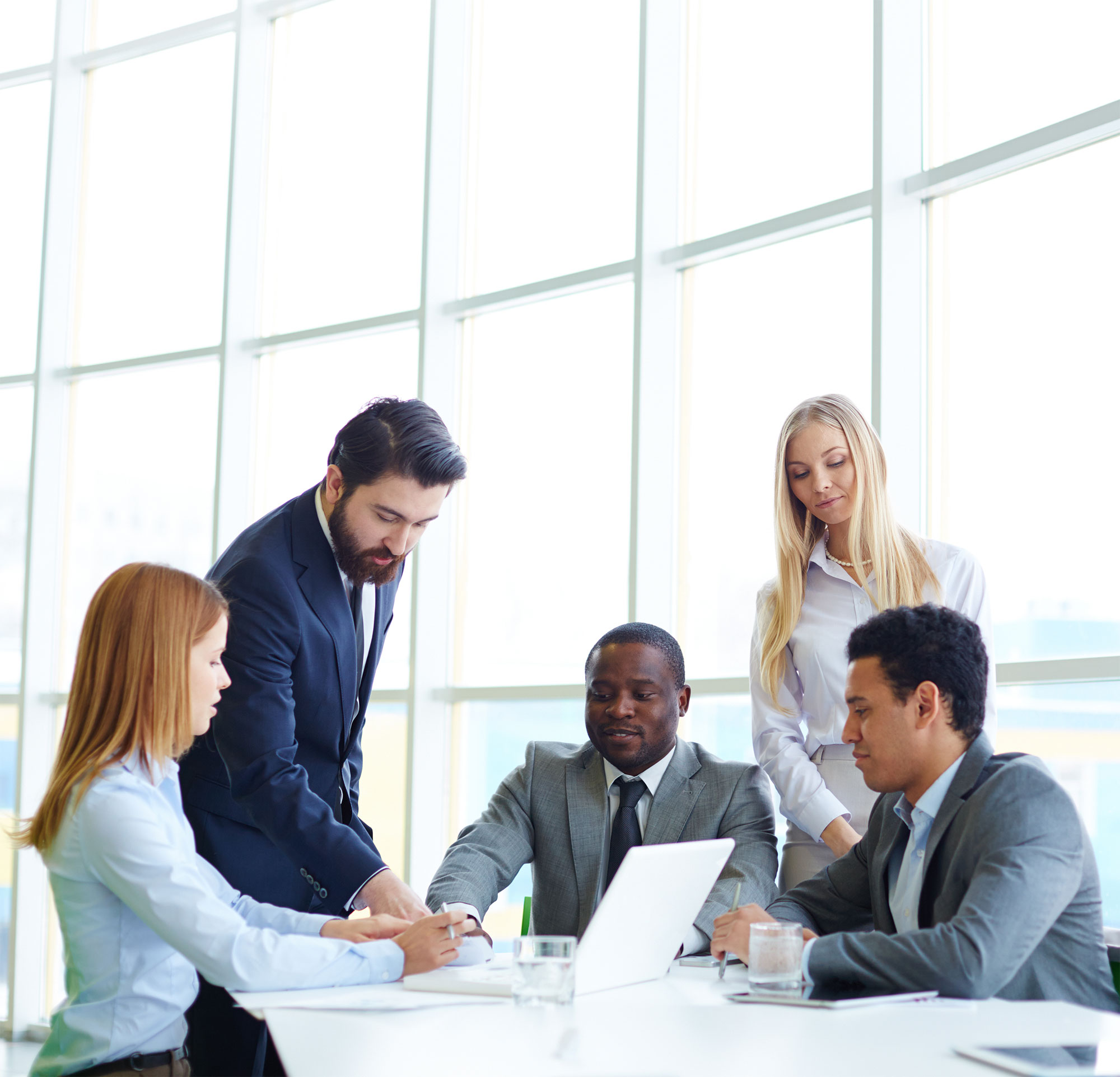 Professionals collaborating around a laptop in a meeting