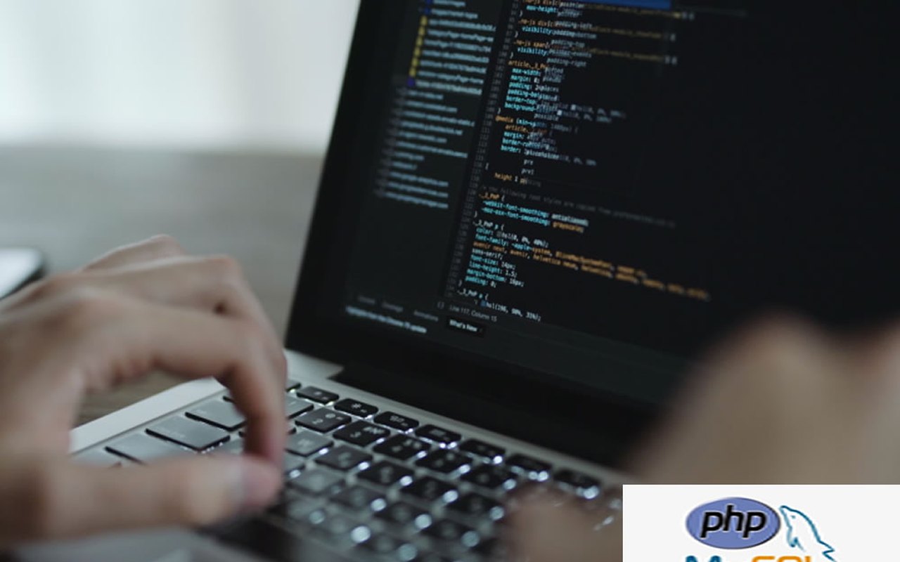 Hands typing code on a laptop with PHP and MySQL logos, illustrating web development training